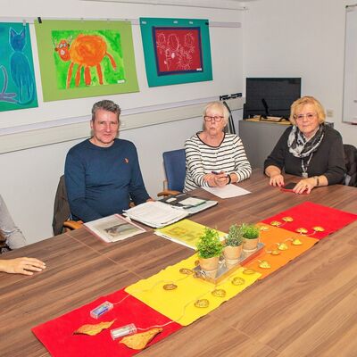5 Personen sitzen an großem Tisch.