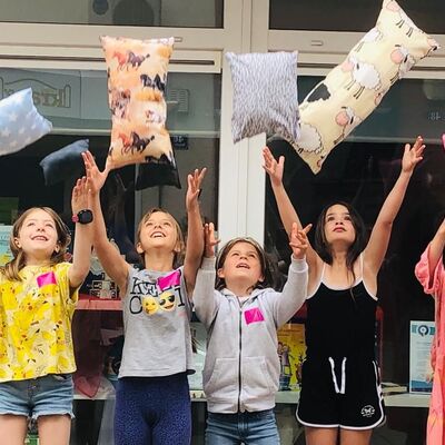 Bild mit lachenden Kindern, die selbst genähte bunte Kissen in die Luft werfen