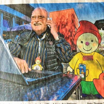 Mann mit Telefon in der Hand, daneben Logo mit Heinzelmännchen)
