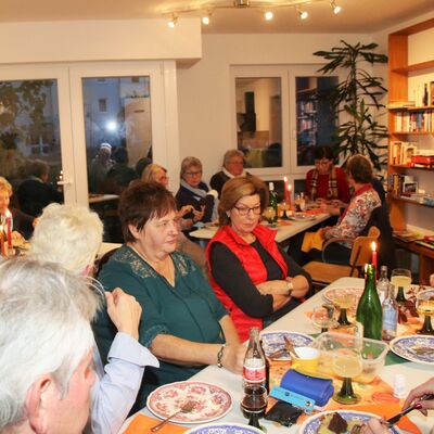 Menschen der Bewohnergemeinschaft sitzen an Tischen bei einem gemeinsamen Treffen zum Speisen.