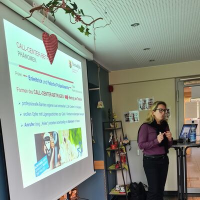 Frau mit Mikrofon präsentiert über Beamer Infos auf Leinwand