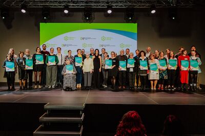 Gruppfenfoto mit vielen Menschen, die eine Preisurkunde in der Hand halten