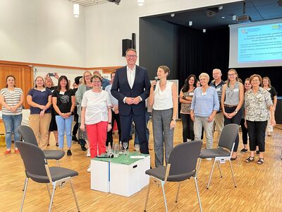 Im Tagungsaal aufgenommenes Gruppenfoto. Um den sehr großen Minister im Anzug stehen etwa rund 30 Frauen und Männer, die an der Fachtagung teilgenommen haben