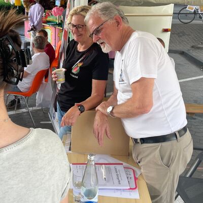 Ein Mann und eine Frau stehen an einem Stand und unterhalten sich.