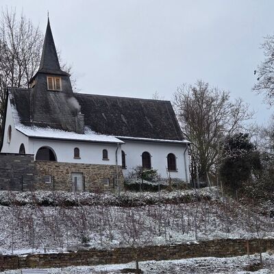Kleine weiße Kapelle auf einem Hügel mit Weinreben in Winterlandschaft mit Schnee.