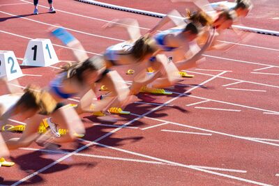 Sprinterinnen in Bewegung (Unschärfe) beim Start aus Startblöcken.