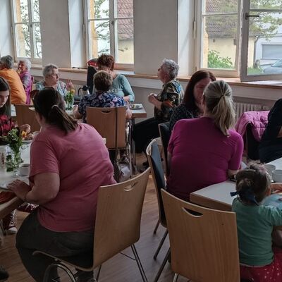 Menschen allen Alters sitzen an Tischen bei Kaffe und Kuchen