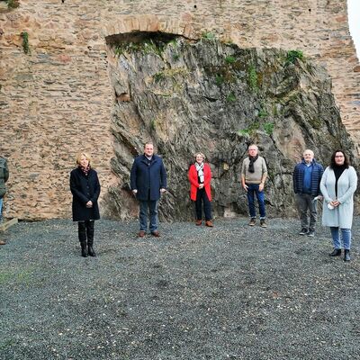 7 Personen stehen vor altem Gemäuer auf Felsen