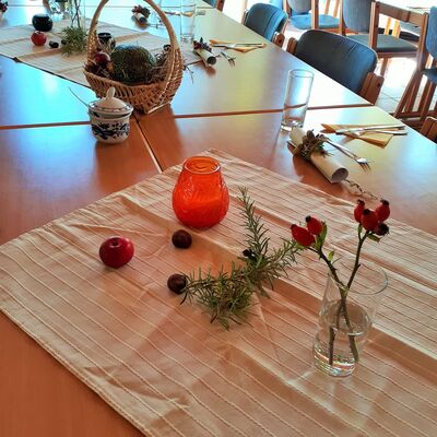 Frühherbliche Tischdekoration mit Äpfeln, Hagebutten und gerollten Menükarten mit Blumenbucket