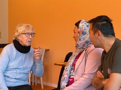 Älterer Frau unterhält sich mit jüngerer Frau und Mann mit Migrationshintergrund