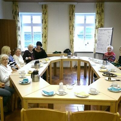 Neun Frauen an einer runden Kaffeetafel