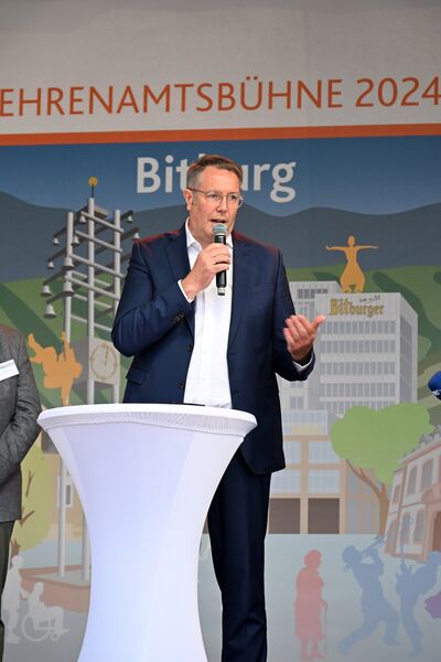 Mann im Anzug und mit Mikrofon auf einer Bühne