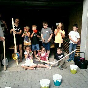 Gruppenfoto von acht Kindern mit selbstgebasstelten Musikinstrumenten mit ihren Anleitern.
