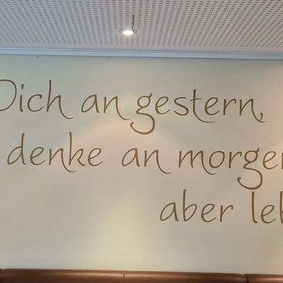 Spruch an der Wand: Erinnere dich an gestern, denke an morgen, aber lebe heute.