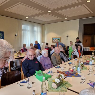 Bild mit gedeckten Tisch an dem Senioren und Seniorinnen sitzen