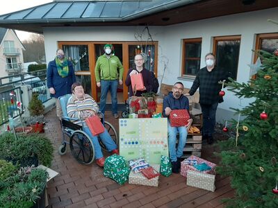 Gruppenfoto, alle mit Maske, von Menschen mit Behinderung und den überreichern von Weihnachtsgeschenken