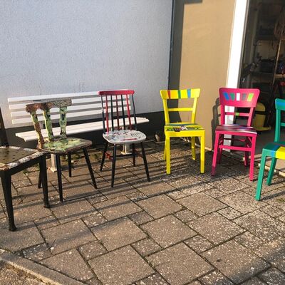6 diverse bunt gestaltete Stühle auf einer Terasse