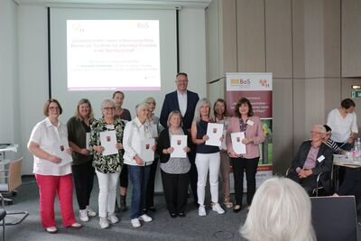 Gruppenbild von Frauen die Urkunden in der Hand halten, mittendrin ein großer Mann in Anzug.