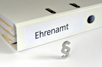 Aktenordner auf dem Ehrenamt steht, davor ein Praragrafensymbol