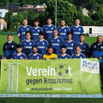 Fußballteam hält Plakat "Vereint gegen Rassismus"