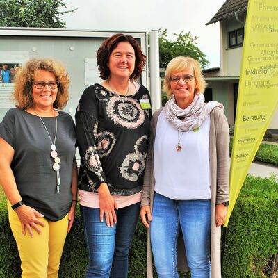 Gruppenbild mit drei Frauen und Aufsteller