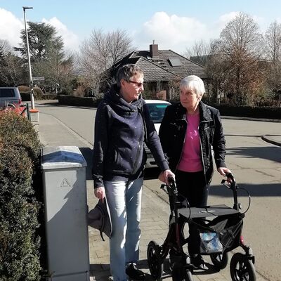 Frau begleitet ältere Frau am Rollator