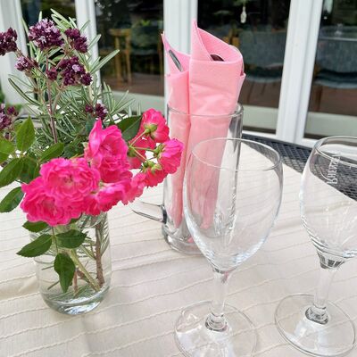 Bunter Sommerblumenstrauß, pinke Serviette im Glas und 2 leere Stilgläser