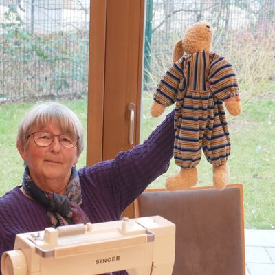 Bild mit Frau an Nähmaschine, die einen Stoffhasen in die Höhe hält