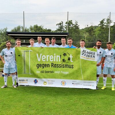 Fußballteam hält Plakat "Vereint gegen Rassismus"