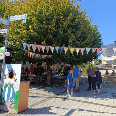 Girlanden geschmückte Straße, Jung und Alt unter Bäumen