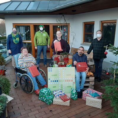 Gruppenfoto, alle mit Maske, von Menschen mit Behinderung und den überreichern von Weihnachtsgeschenken