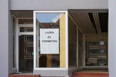 Fensterfront eines leerstehenden Ladenlokals mit Schild im Fenster auf dem Laden zu vermieten steht