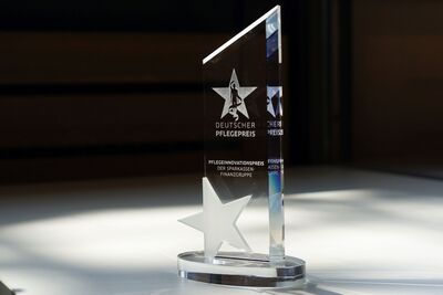 Durchsichtiger Pokal in Form einer 1 mit eingravierten Sternen und Inschrift Deutscher Pflegepreis