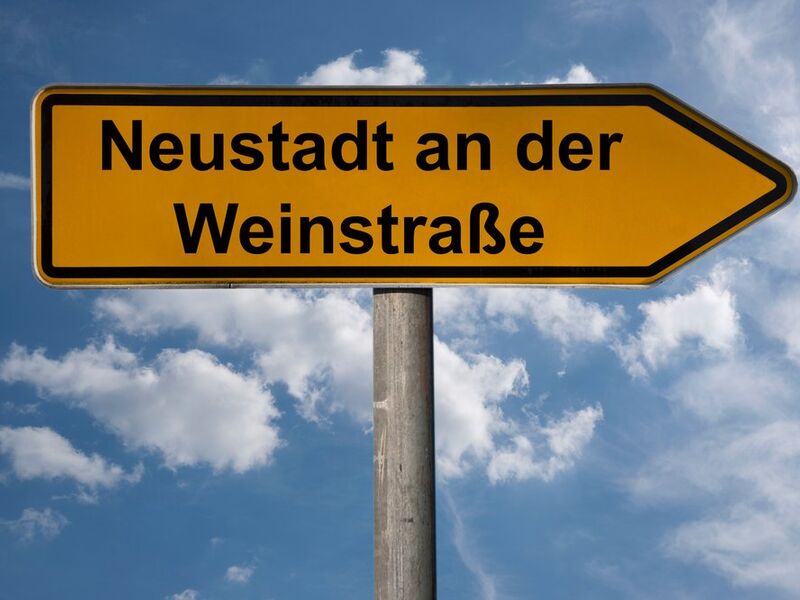 Gelbes Ortsschild Neustadt an der Weinstraße vor blauem Himmel