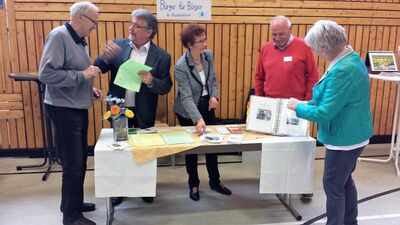 Fünf Personen im Gespräch an einem Stand.