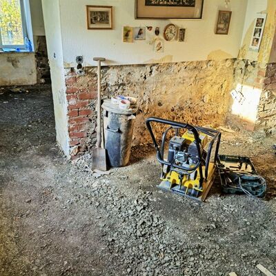 Schaufel, Mülleimer und Rüttelmaschine auf dem bodenlosen Wohnzimmer