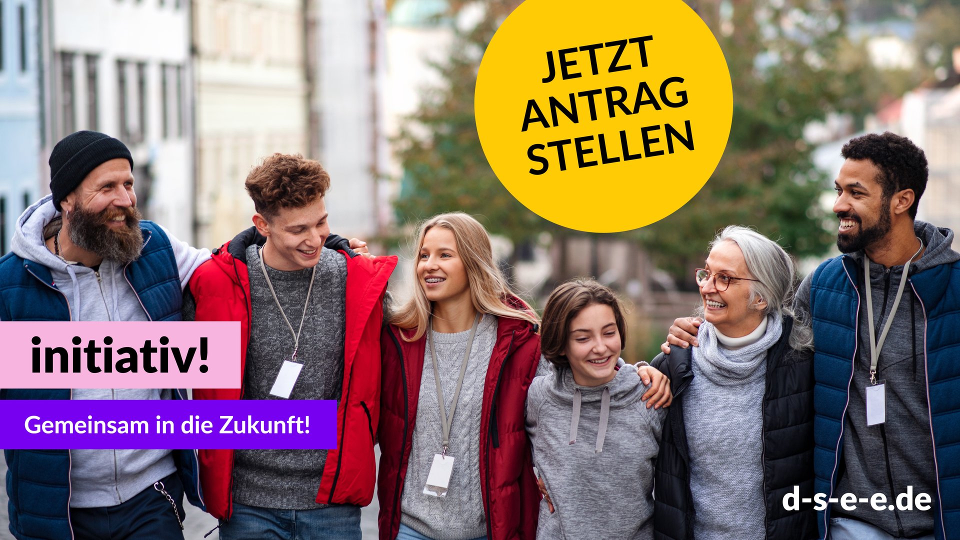 fünf Menschen unterschiedlichen Alters und unterschiedlicher Herkunft halten lachend nebeneinander und haben sich umarmt
