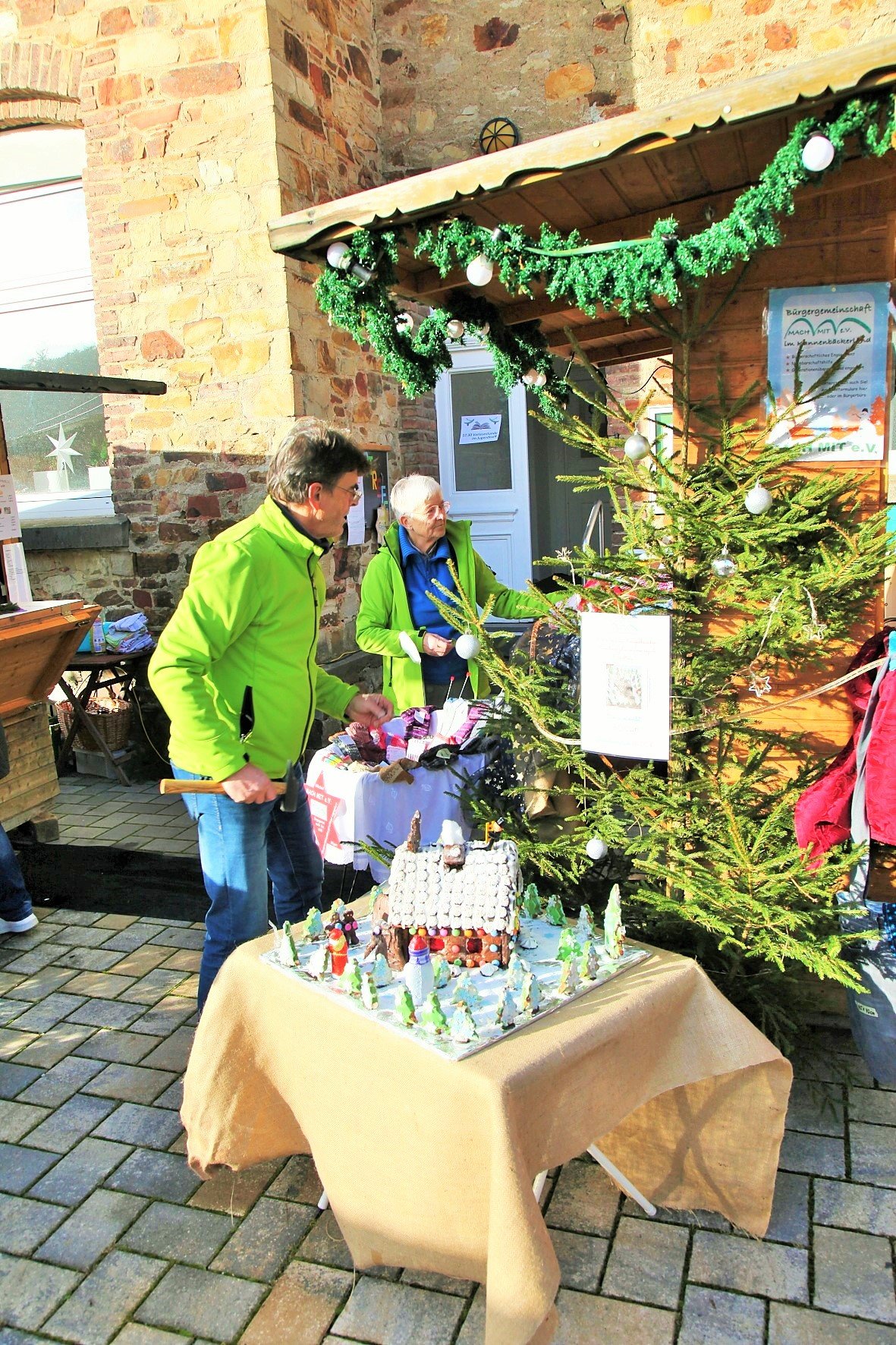 Mann und Frau in Grüner Jacke bauen Weihnachtsbude auf.